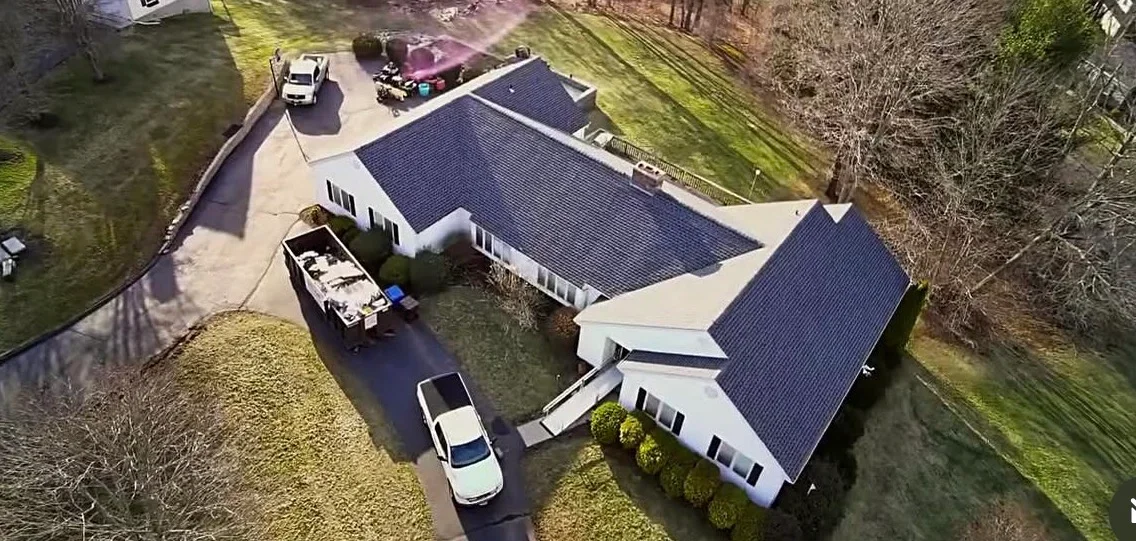 Aerial view of residential home with newly installed dark shingle roof and white trim