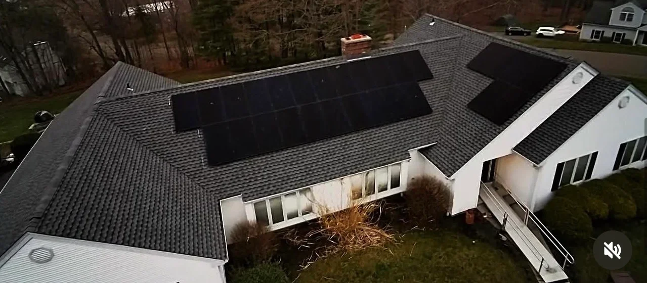 Aerial view of residential roof with new gray shingles and black solar panels installed